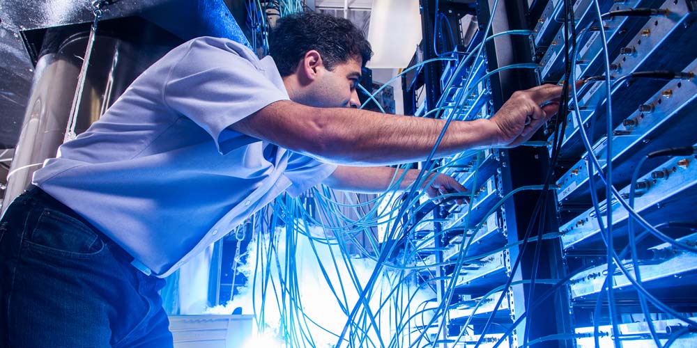 A researcher adjusting connectinos on a computer server rack.