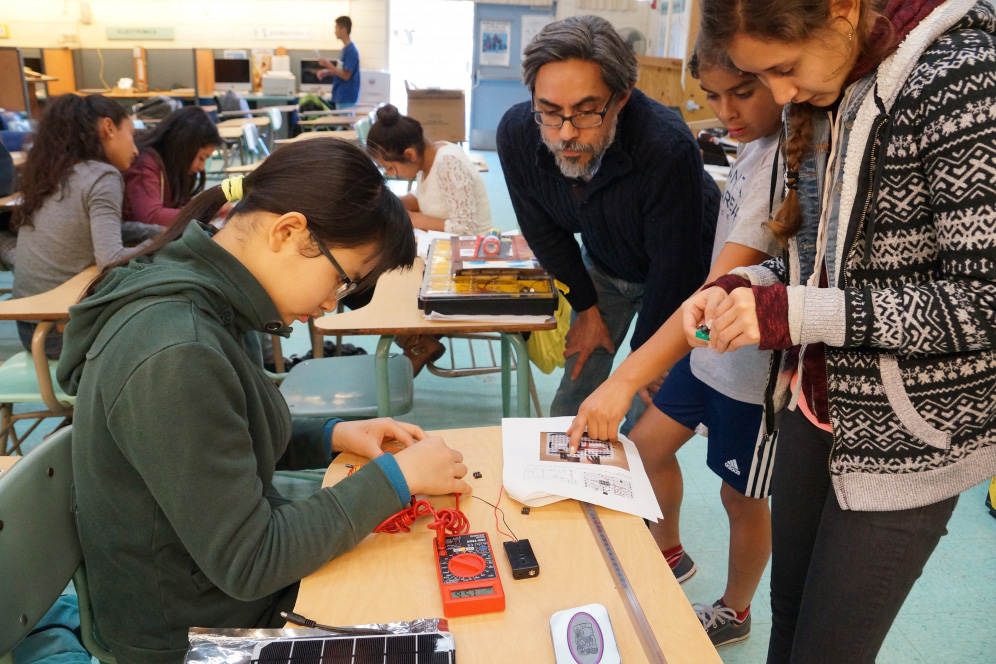 Professor Gerardo Aldana, center, looks on while UCSB undergradate and mentor Leslie Lopez, far right, works with Goleta Valley Junior High School students.