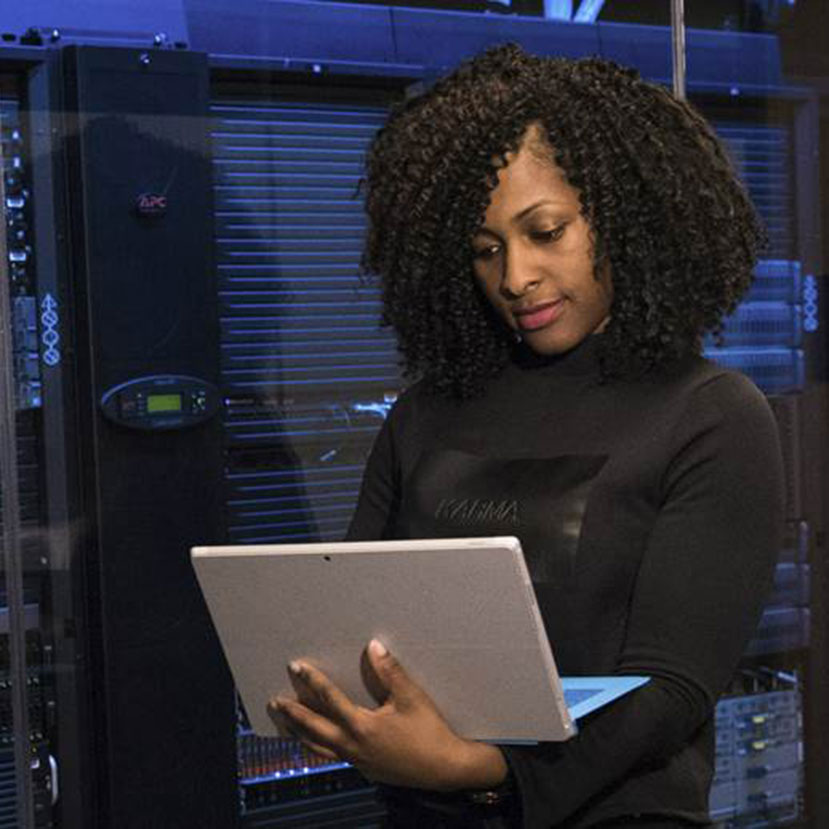 A person next to a Rack of computers in a data center.